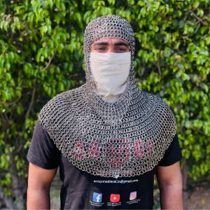 May include: A silver chainmail coif, a type of medieval head and neck protection. The coif is made of small, interlocking metal rings and covers the head, neck, and shoulders. The coif is worn over a brown garment.