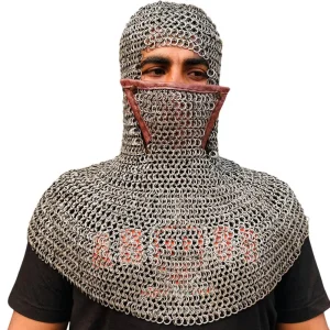 May include: A silver-colored chainmail coif featuring a protective face mask section. The headpiece is constructed from interlocking metal rings and includes a brown leather trim along the upper edge of the face covering, which sits across the nose.